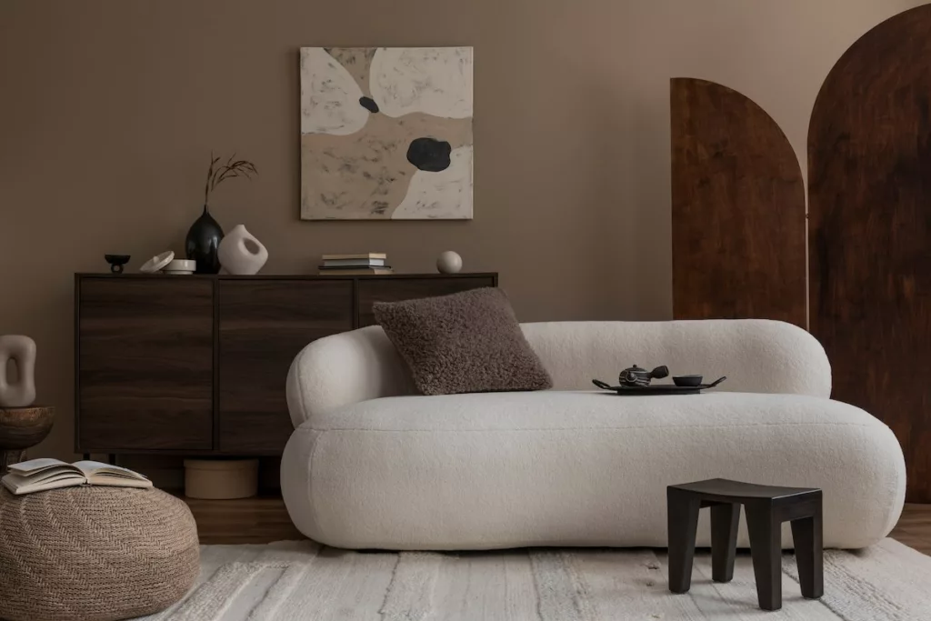 Olohuone, jossa pehmeitä ja pörröisiä sisustustyynyjä ja buklee-pintainen sohva
